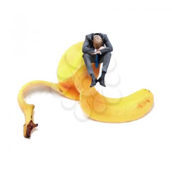 Businessman sitting on banana peel
