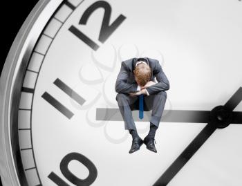 Depressed businessman sitting on a clock