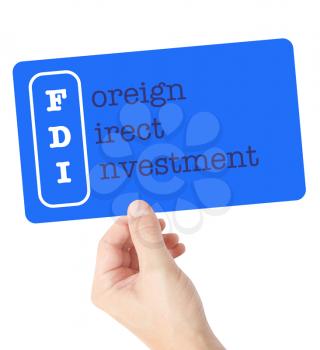 Foreign Direct Investment explained on a card held by a hand