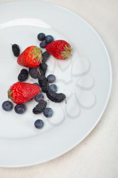 fresh and ripe strawberry mulberry and mulberry on white plate