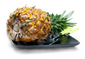 pineapple on a black plate with knife and fork isolated on white background