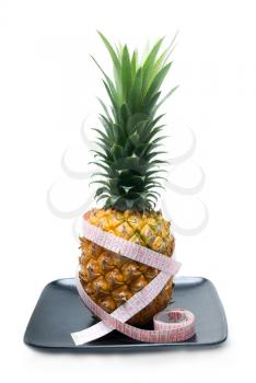 pineapple on a black plate with tape meter isolated on white background