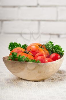 fresh ripe organic  tomatoes on a wood bowl with parsley