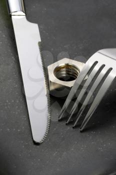 hex nut on a black plate with knife and fork