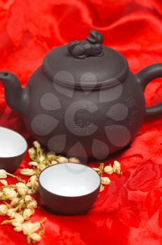 jasmine tea dry flowers,pot and two cups ,over red silk tablecloth
