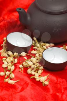 jasmine tea dry flowers,pot and two cups ,over red silk tablecloth