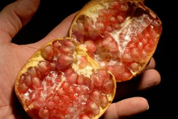 hand holding a pomegranate fruit open in half
