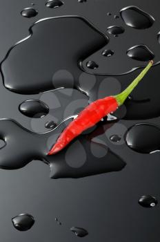 red chili pepper on water drops over a black stone