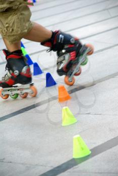 young guy skating slalom around colorfull cones