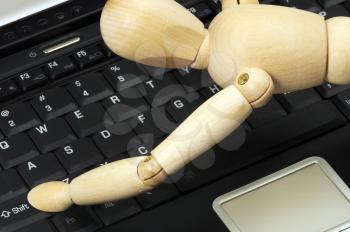 wood mannequin on a laptop reaching for the shift key 