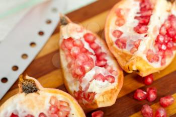 fresh pomegranate fruit over wood cutting board with knife