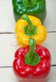 three fresh bell peppers over old wood table