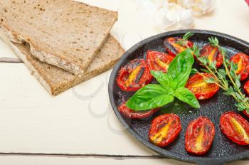 oven baked cherry tomatoes with basil and thyme on a cast iron skillet