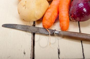 basic vegetable ingredients carrot potato onion on a rustic wood table
