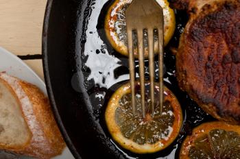 pork chop seared on iron skillet with lemon and spices seasoning