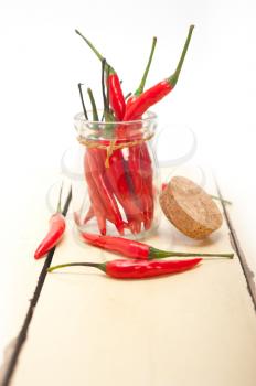 red chili peppers on a glass jar over white wood rustic table