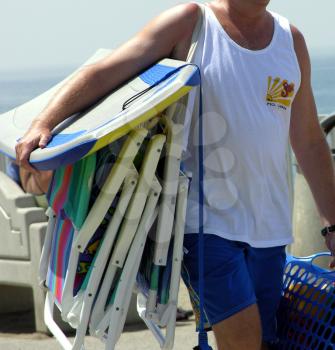 Royalty Free Photo of a Man Carrying Beach Chairs