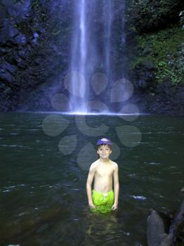 Royalty Free Photo of a Boy Standing in Water by a Waterfall
