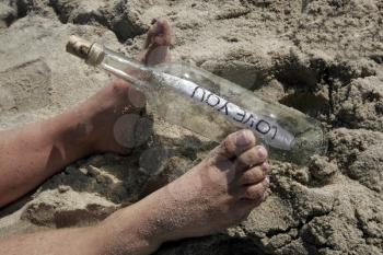 Royalty Free Photo of Sandy Feet and Message in a Bottle