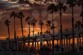 Royalty Free Photo of an Oceanside Pier at Sunset with Palm Trees