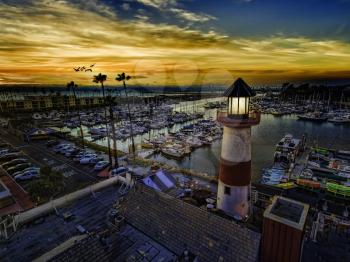 Royalty Free Photo of Pelicans gliding over the Oceanside Harbor and the little lighthouse glows. Colorful sunset in Oceanside, California, USA.