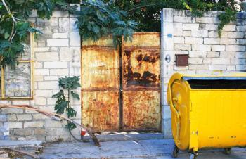 Royalty Free Photo of a Rusty Gate and Garbage Bin