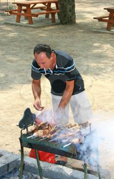 Royalty Free Photo of a Man Cooking Meat on a Barbecue