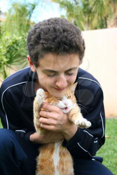 Royalty Free Photo of a Teenage Boy Hugging a Cat