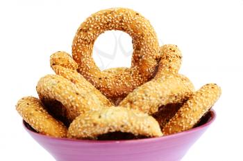 Round rusks with sesame seeads in pink bowl isolated on white background.