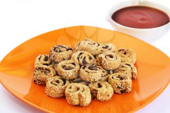 Rusks with sesame seeds, olives on orange plate and red sauce isolated on white background.