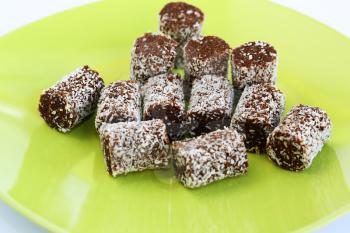 Coconut and chocolate candies on green plate.