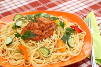Spaghetti pasta with sauce and vegetables on table.