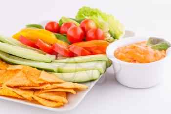 Nachos, vegetables and cheese sauce isolated on gray background.