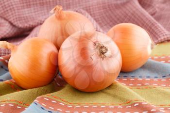 Four onions on colorful towel.