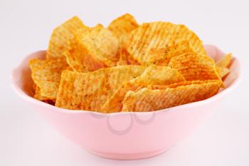 Potato chips in pink bowl isolated on gray background.