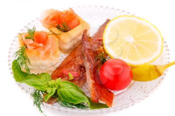 Smoked fish with fresh vegetables and lemon on plate.