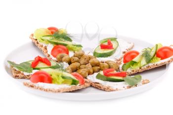 Cracker with fresh vegetables and cream on plate isolated on white background.