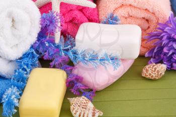 Colorful rolled towels with flowers and soaps closeup picture.