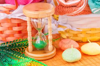 Spa set with colorful towels, candles and sandglass on bamboo background.