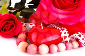 Red heart candles, wooden necklace, ribbon and roses on white background.