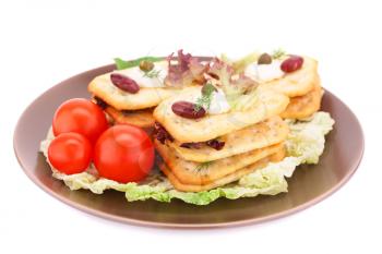 Crackers with fresh vegetables and cream on brown plate.