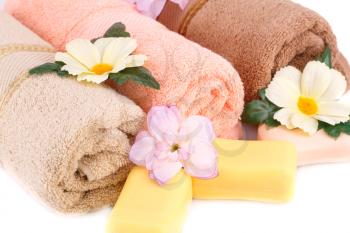 Rolled towels, soaps and flowers closeup picture.