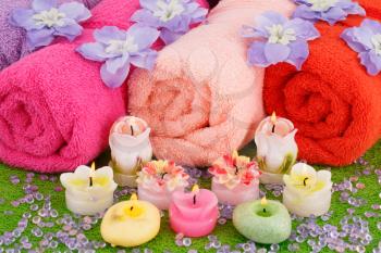 Spa set with towels, candles and flowers on plastic background.