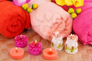 Spa set with towels, candles and flowers on bamboo background.
