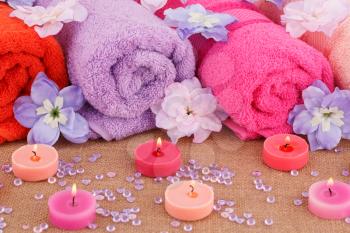 Spa set with towels, candles and flowers on canvas background.