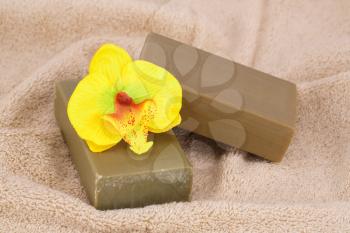 Organic soaps and orchid flower on beige towel.