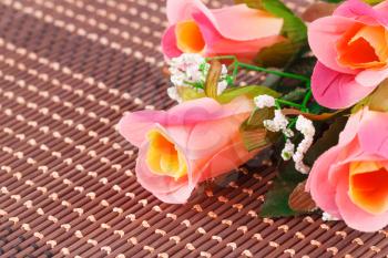 Colorful fabric roses on bamboo background, closeup picture.