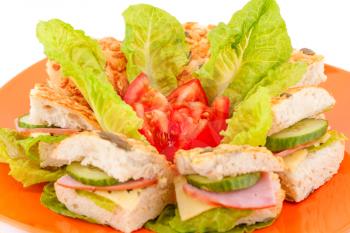 Sandwiches with fresh vegetables, ham and cheese on plate.