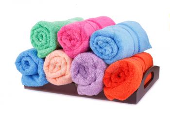Rolled colorful towels in wooden tray isolated on white background.