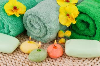 Spa set with towels, candles, soaps and flowers on bamboo background.